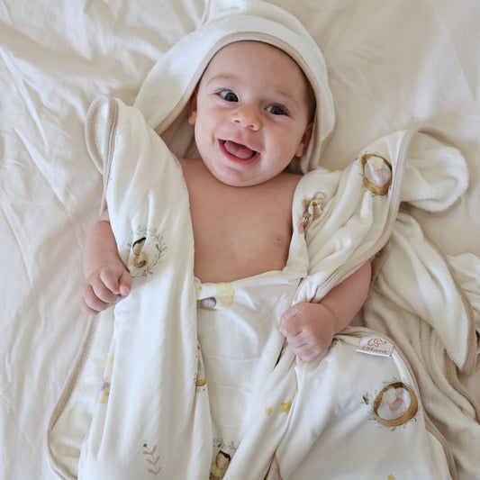 soft colours, baby is laying on a soft surface, covered with a towel